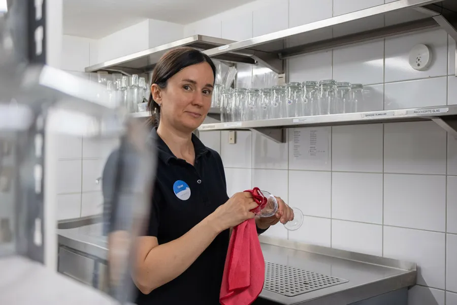 Mitarbeiterin trocknet Weingläser im Servicebereich des Strandhaus Ahrenshoop.