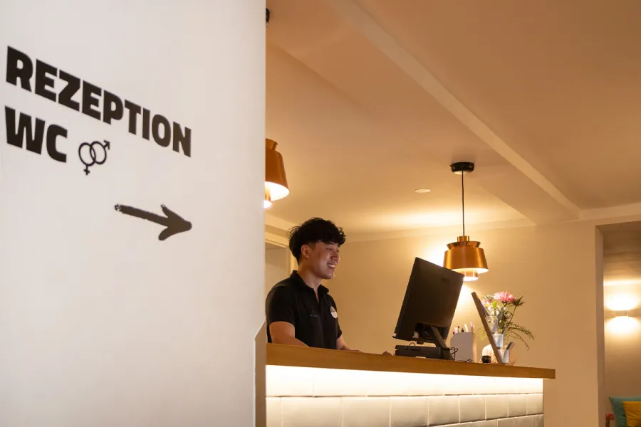 Mitarbeitender an der Rezeption des Strandhaus Ahrenshoop begrüßt Gäste am Empfang.