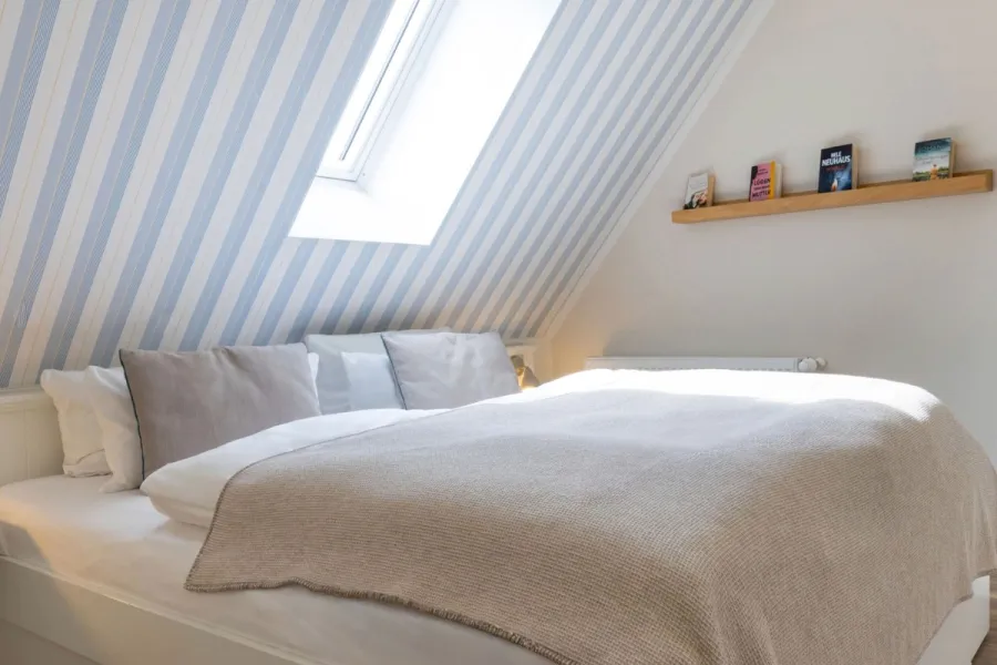 Helles Familienzimmer im Boutique-Hotel STRANDHAUS Ahrenshoop auf dem Fischland-Darß-Zingst mit Doppelbett und blau-weißer Streifentapete.
