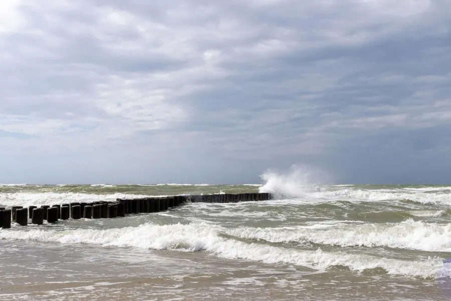 Aufgewühlte Ostsee mit Buhnen und Gischt bei grauem Herbstwetter am Strand auf dem Fischland-Darß.