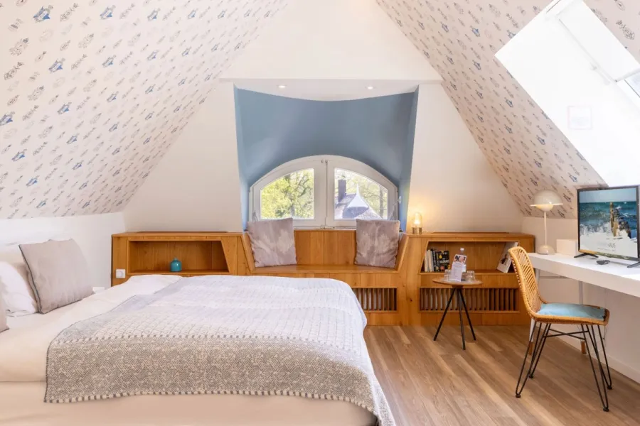 Helles Dachzimmer Landseite im Boutique-Hotel STRANDHAUS Ahrenshoop auf dem Fischland-Darß-Zingst mit Doppelbett, Holzbank und Dachschräge.