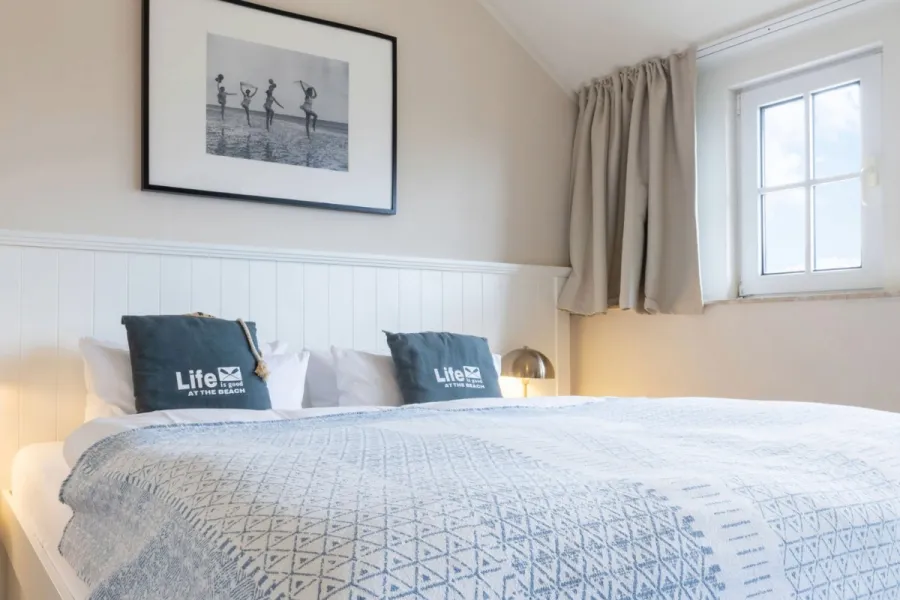 Doppelzimmer im Boutique-Hotel STRANDHAUS Ahrenshoop auf dem Fischland-Darß-Zingst mit Doppelbett und warmer Beleuchtung.