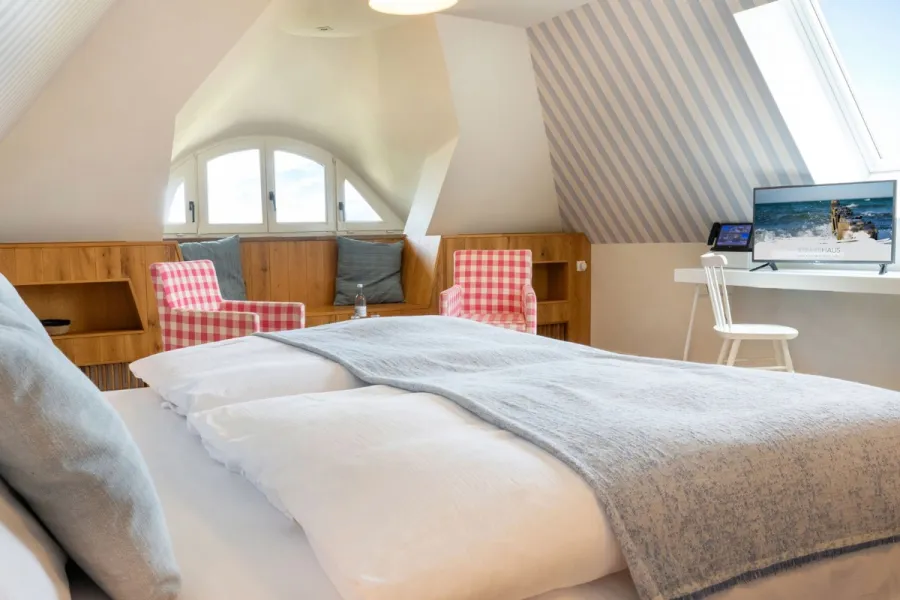 Geräumige Familiensuite im Boutique-Hotel STRANDHAUS Ahrenshoop auf dem Fischland-Darß-Zingst mit Dachschräge und blau-weißer Tapete.