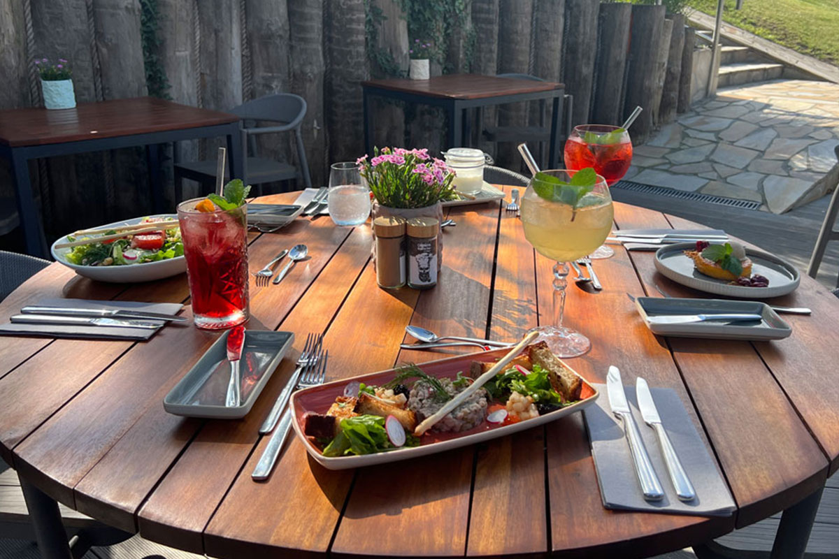 Gedeckter Tisch mit Speisen und Cocktails auf der Sonnenterrasse im STRANDHAUS Ahrenshoop.
