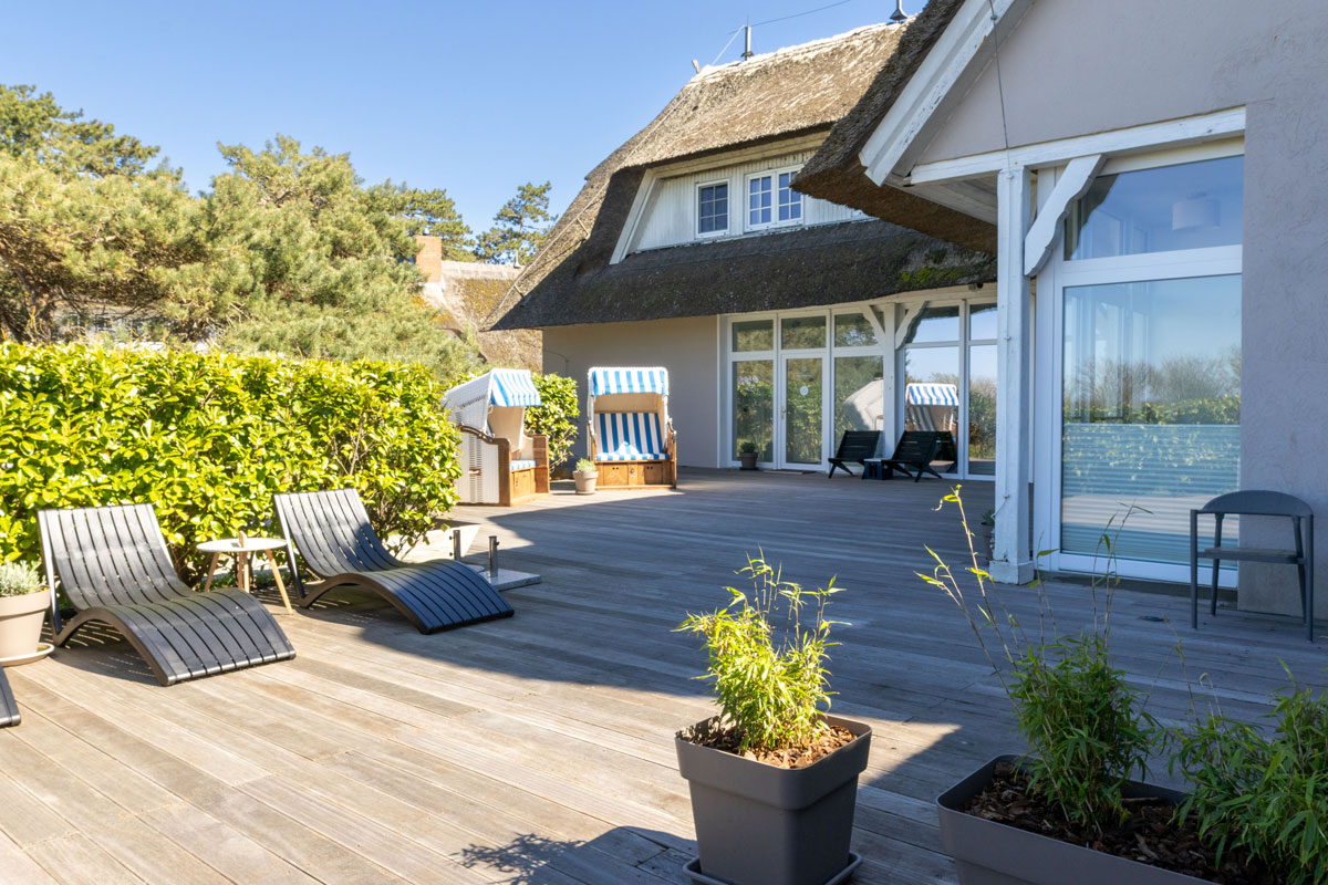 Sonnenterrasse mit Liegen und Strandkörben vor dem Reetdachhaus des STRANDHAUS Ahrenshoop.